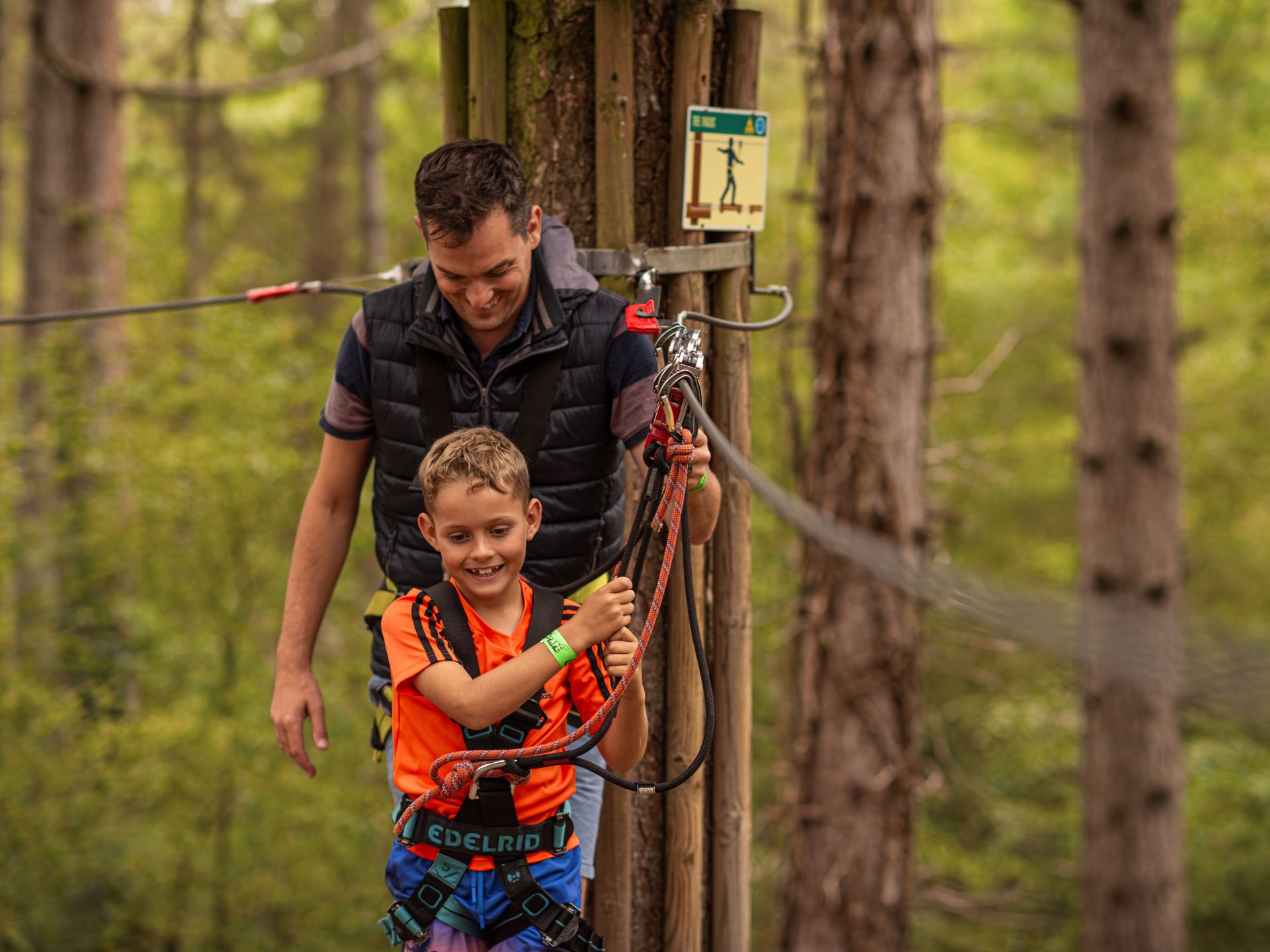 a man and a child on a Go Ape tree top crossing in the forest