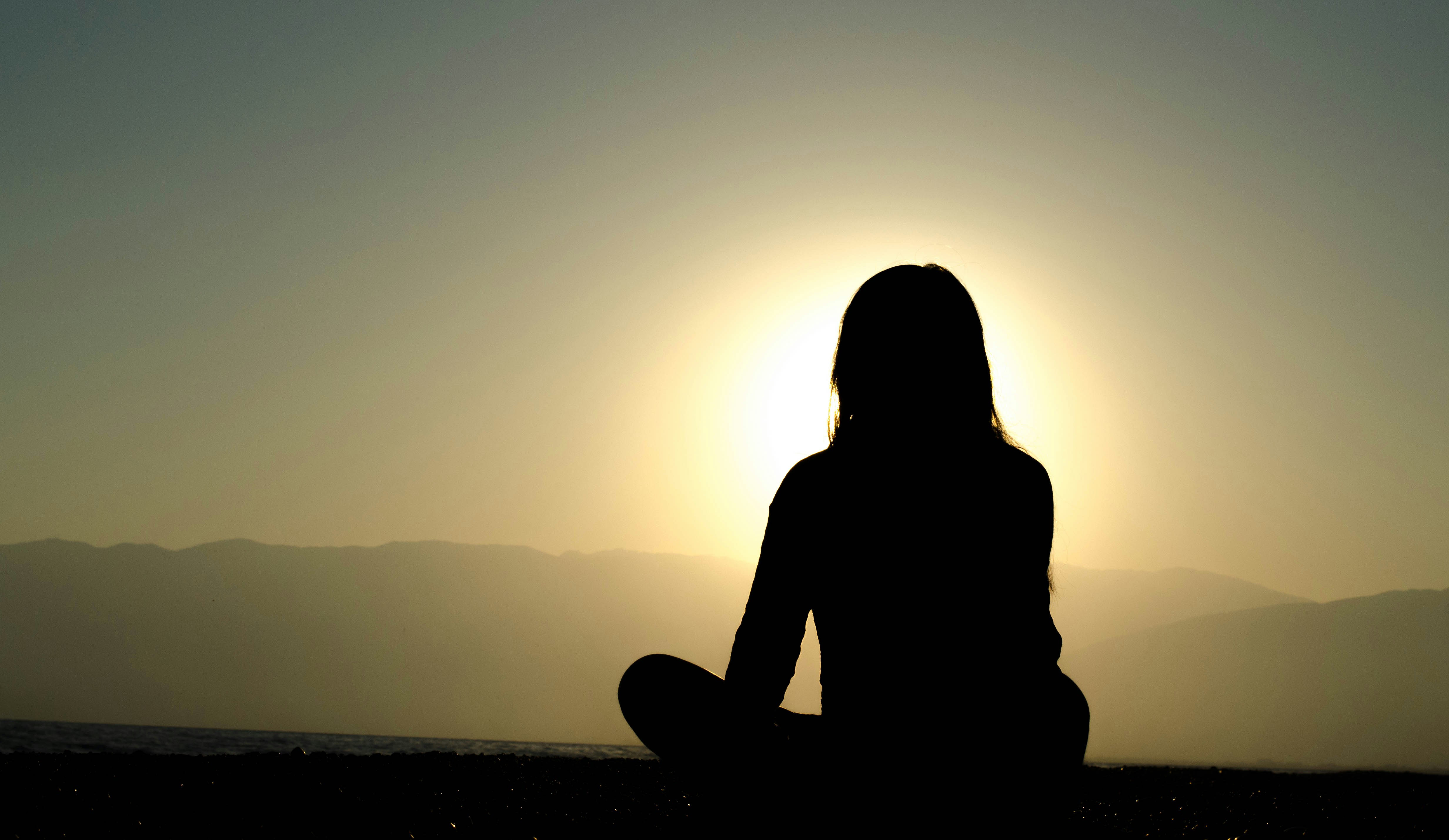 Person meditating by the sunset | stress awareness month