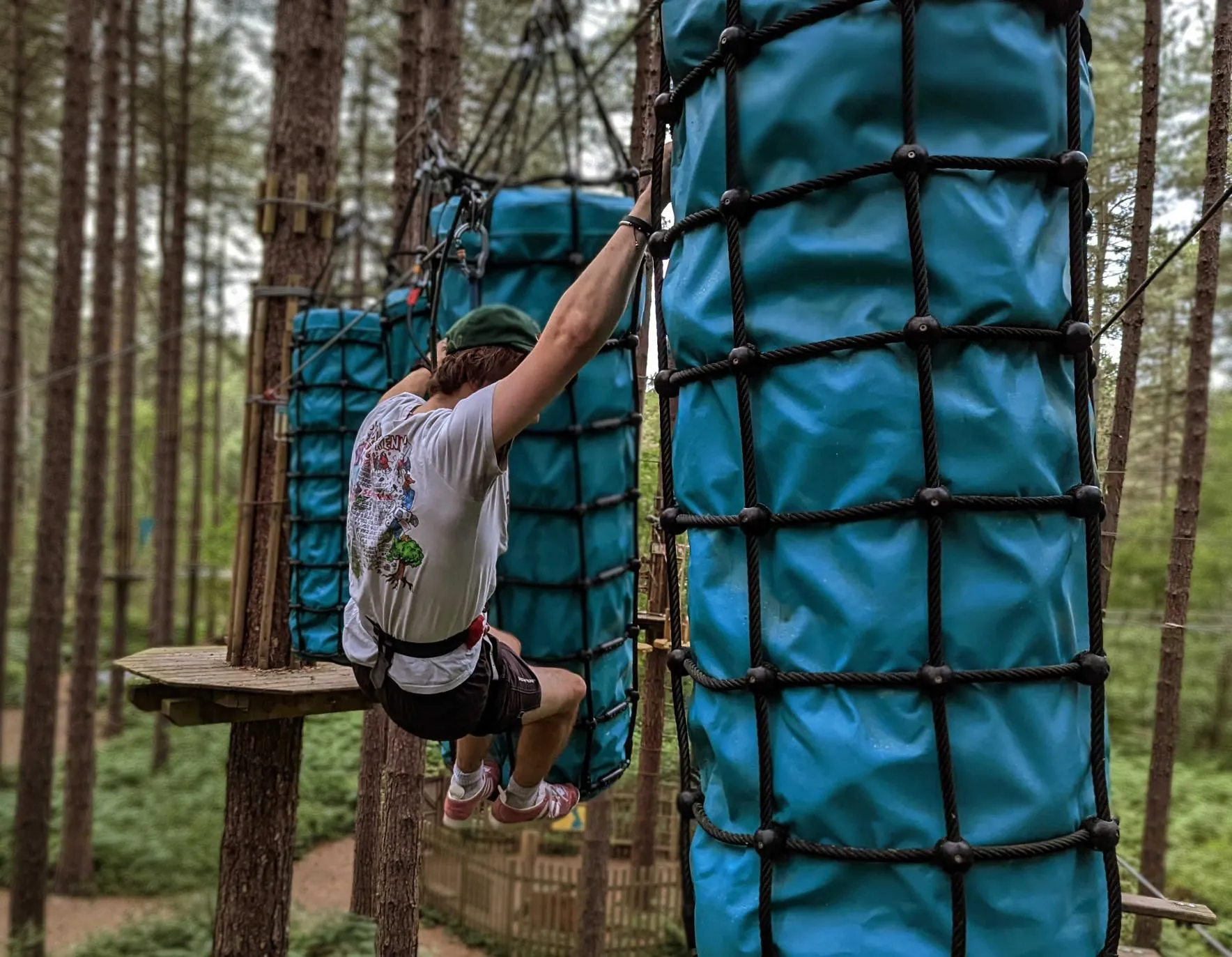 Man climbing across Treetop Challenge Plus course