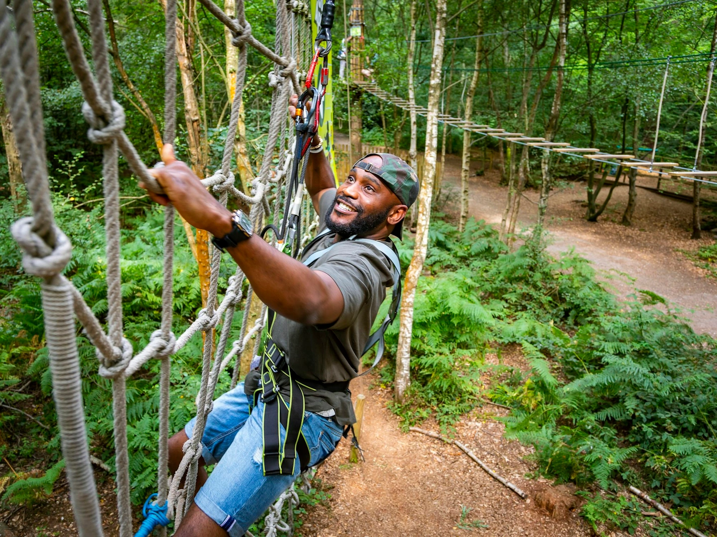 Person climbing a cargo net on a high ropes course.