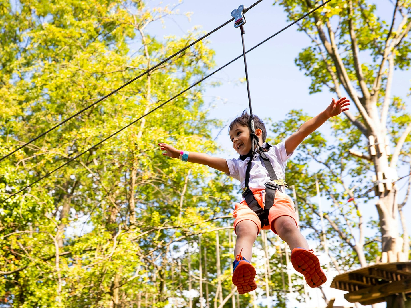 Young person on a zipline while smiling.