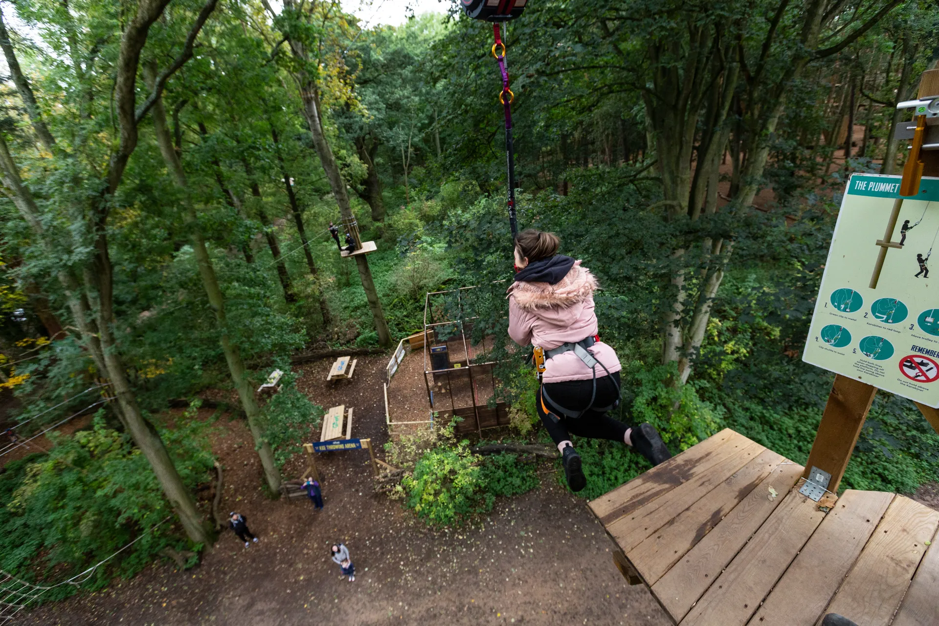 Person steps from a high platform wearing a harness.