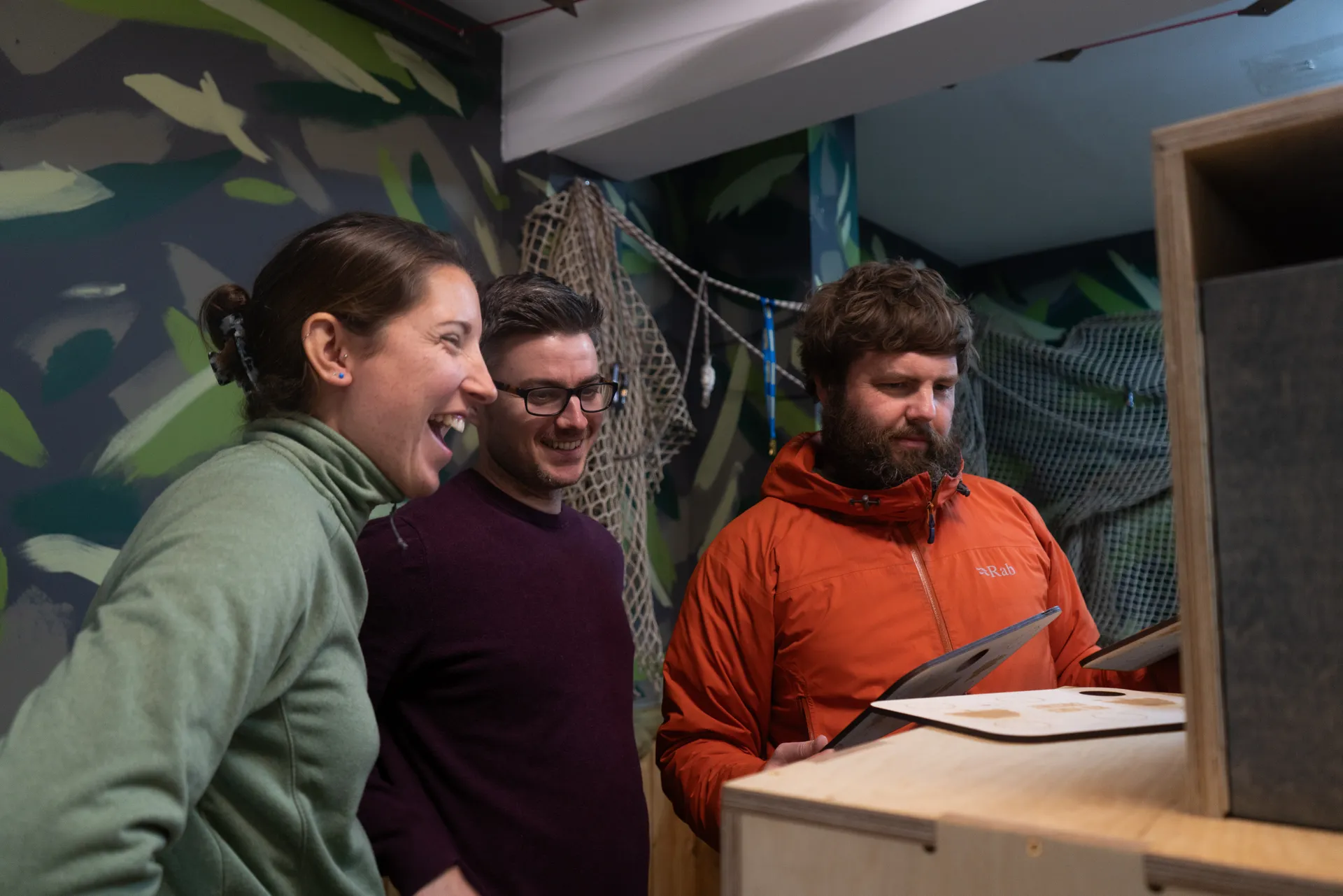 Three people laugh while solving a puzzle.