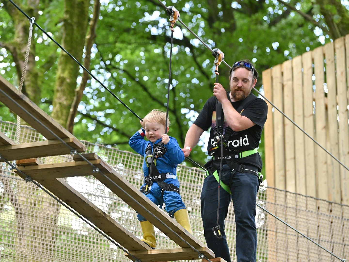 Child on a high ropes course while an adult supervises.