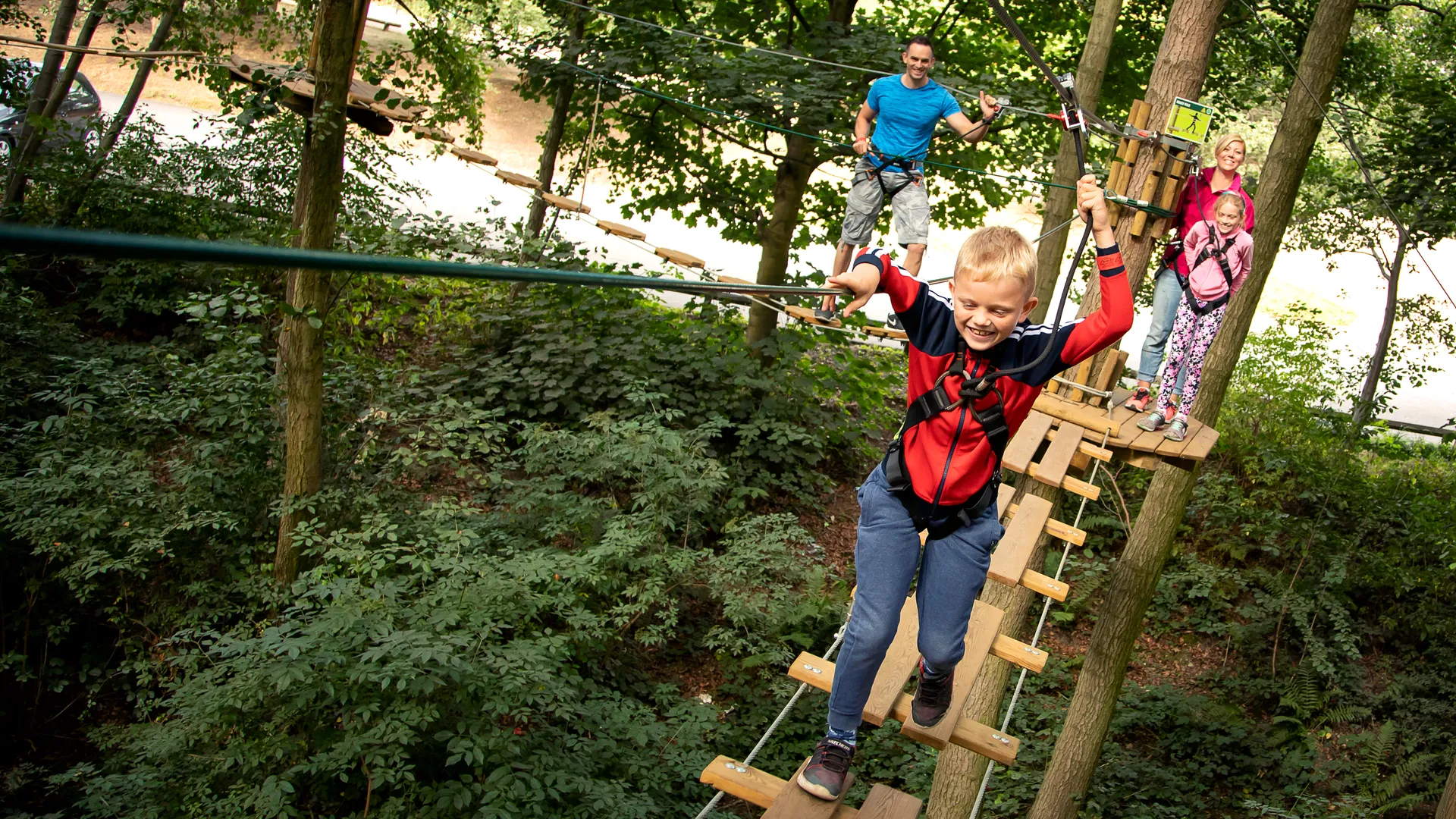 Young people and two adults on a high ropes course.