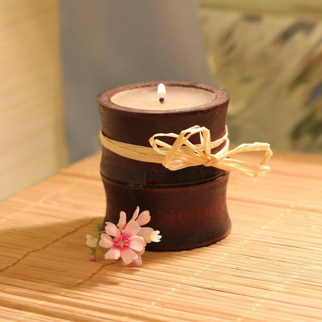 A candle on a bamboo mat with a flower resting nearby