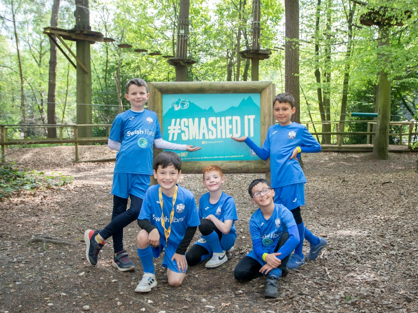 A group of young team mates celebrate their Go Ape visit by the #SmashedIt sign