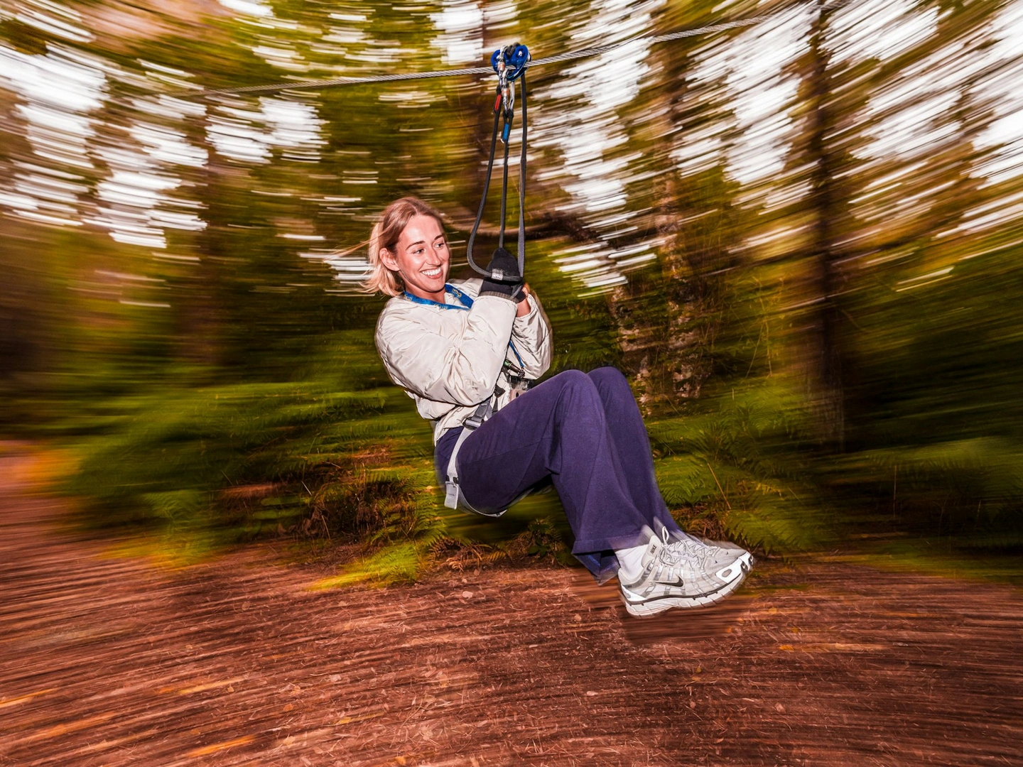 A woman enjoys a fun zip wire ride in the forest