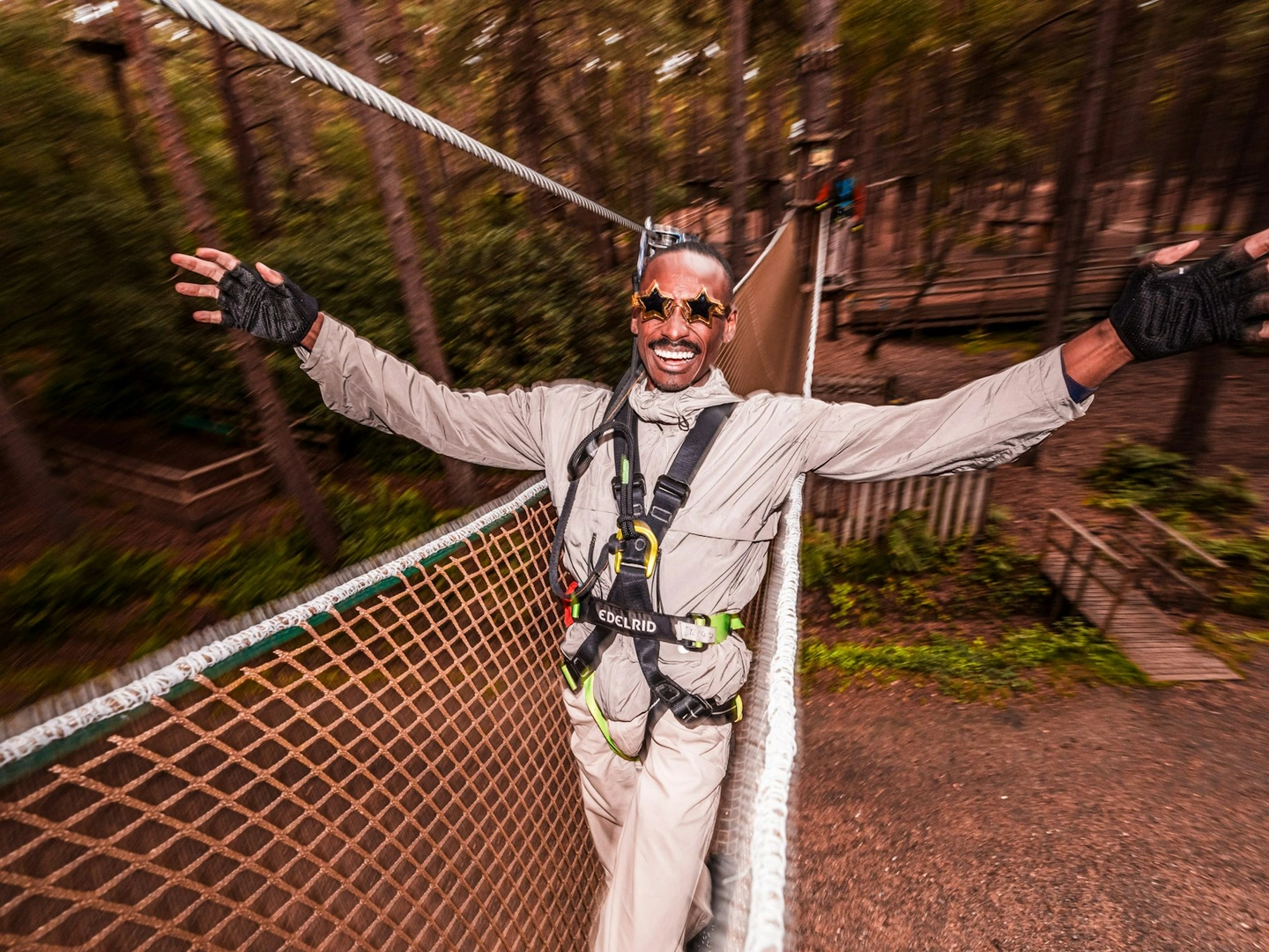 A man holds out his arms and smiles ona  fun day out in the treetops at Go Ape