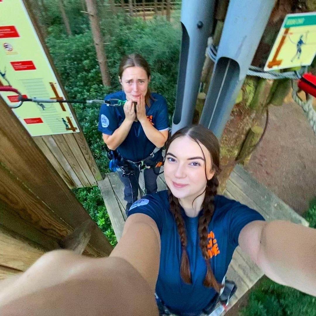 two Go Ape instructors taking a selfie on a Tarzan Swing platform in the trees