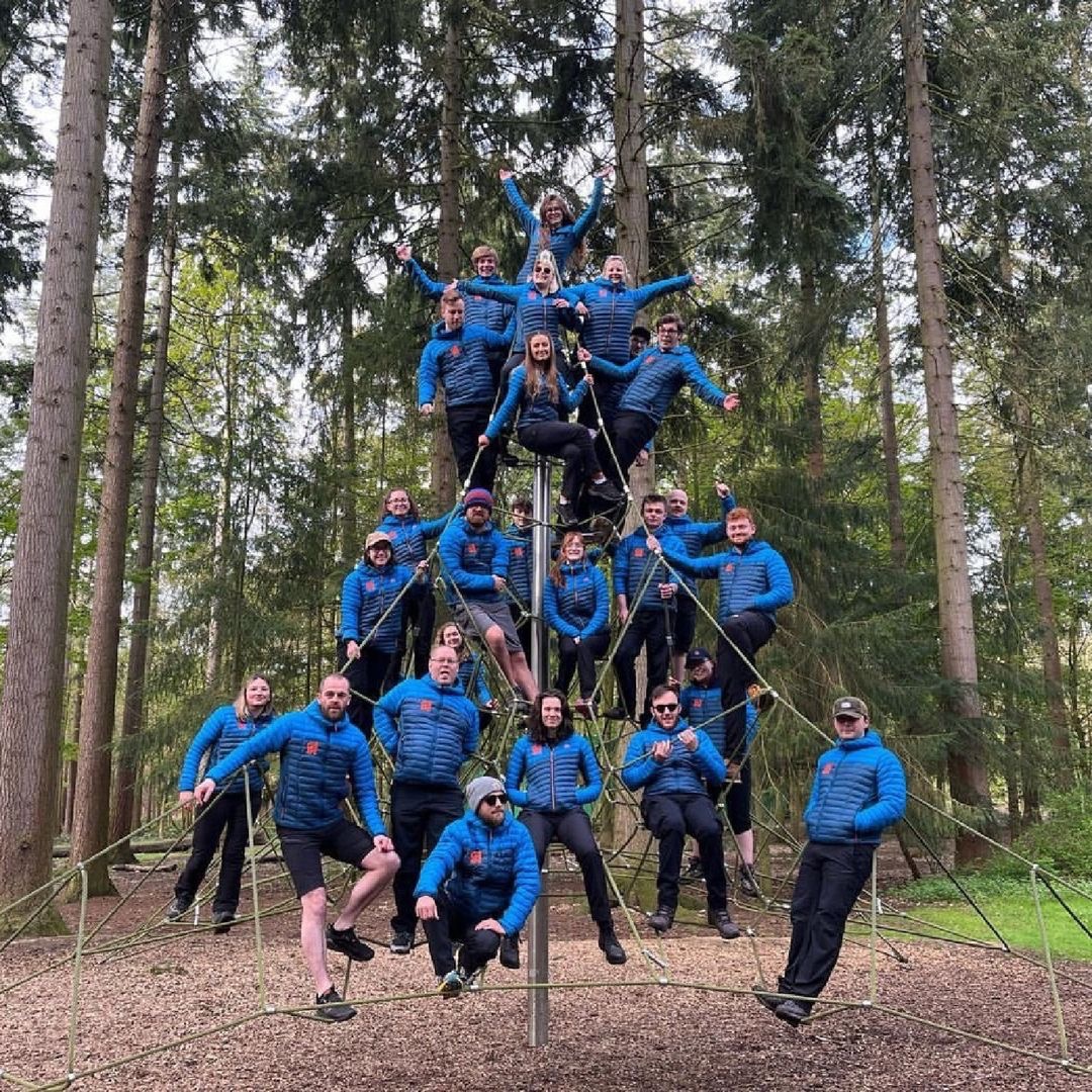 a group of Go Ape instructors in their new blue uniforms on a sapce net ina childrens play area