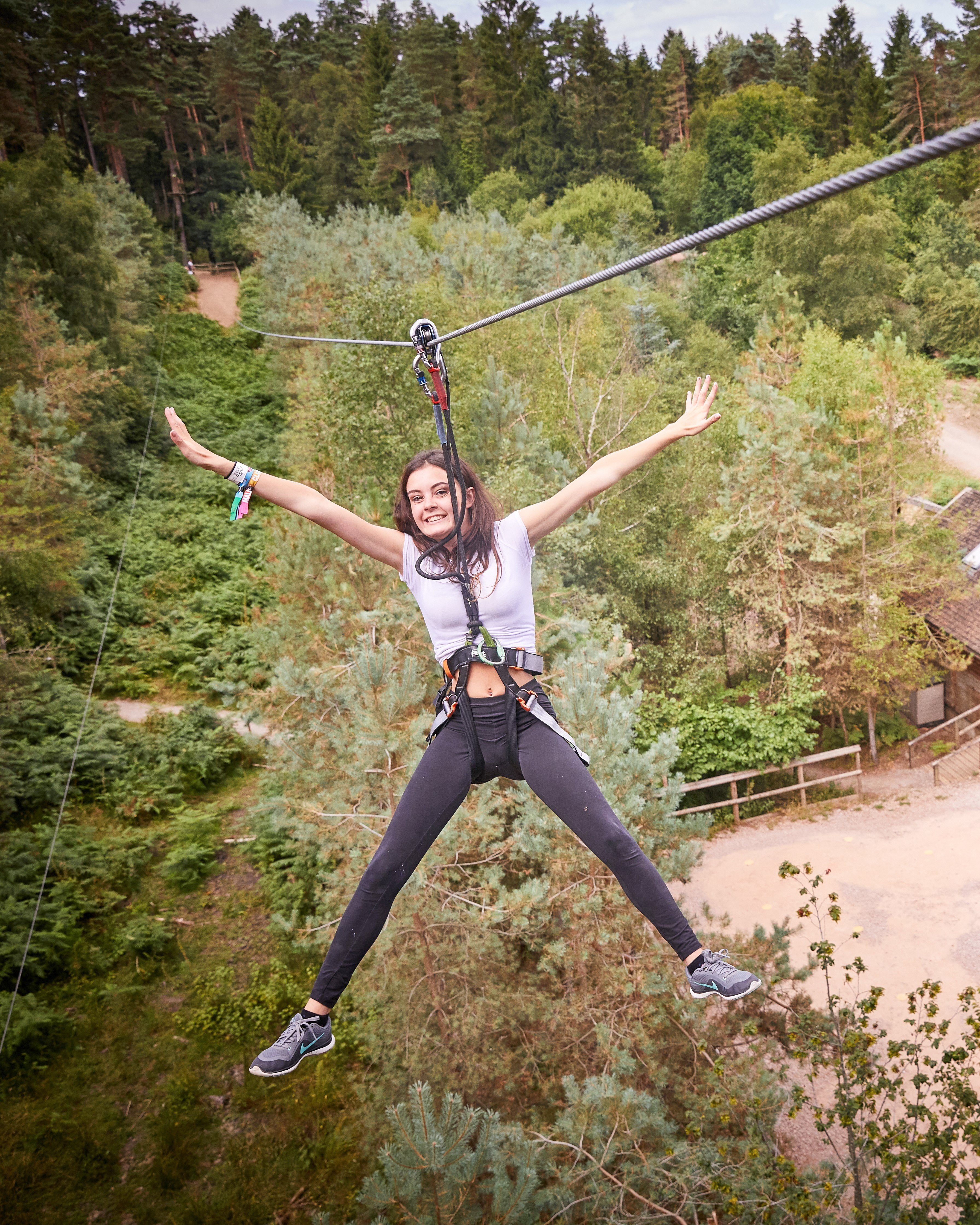 a woman having a fun time on a Go Ape zip wire, a great day out if you're searching for zip wire near me
