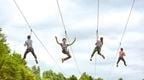 A group of four people riding the quad zip wires at Go Ape Chessington