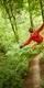 A man in a red top with his arms spread risding a Go Ape zip wire