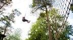 Person on Go Ape Treetop Challenge tarzan swing 