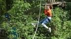 A woman in a Go Ape Treetop Challange high ropes adventure course