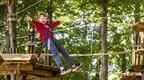 A boy wearing a red top and having fun on Go Ape zip wire at Go Ape Salcey Forest near Northampton and Milton Keynes