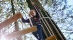 A girl on a Go Ape crossing in the tree tops