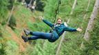 A woman riding a Go Ape Zip Trek zip wire on a fin hen do