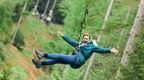 woman in black coat smiling with arms out on Go Ape zip line  | How to plan a hen do