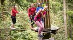 woman in pink laughing on Go Ape crossing with girls watching on behind  | How to plan a hen do
