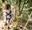 boy smiling to camera wearing harness walking across high bridge in forest.