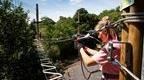 woman in pink tshirt walking over high obstacle course holding safety rope