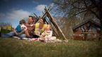 A family enjoying a picnic in a field surrounded by trees