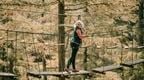 Woman on Go Ape Whinlatter Forest bridge crossing a fun outdoor activity in keswick
