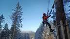 Go Ape Instructor in red doing maintenance on zipline 