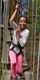 A girl having fun on a Go Ape tree top crossing in the forest