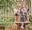 A boy on a Go Ape crossing whilst his family watch on from a platform behind