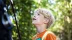 A boy in a Go Ape harness looking up in excitement before his Go Ape high ropes adventure