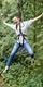 Woman in grey shirt on Go Ape Treetop Challenge zip line 