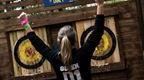 Woman in black hoodie celebrating in fron of axe throwing target