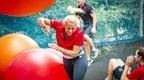 Woman in red top on nets adventure dodging bouncy orange ball
