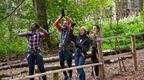 Group of four friends laughing and cheering in the forest 