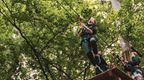 A boy enthusiastically launching down a Go Ape zip wire on a school trip