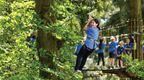 A girl riding a Go Ape zip wire on a school trip