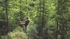 A man with his back to the camera riding down a zip wire