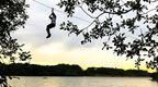 A person on a zip wire ride over a lake at Go Ape Rivington