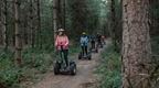 Five adults in a line riding through the forest on forest segways at Go Ape Black Park | fun date ideas in London