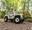A child drives a Go Ape Mini Land Rover through the forest on their summer holidays whilst her mum supervises as a passenger