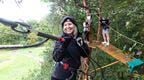 A woman on a Go Ape corssing enjoying her outdoor team day