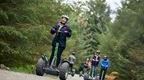 A woman followed by her colleagues riding a Segway on her Go Ape team day