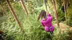 Woman in pink coat on Go Ape Treetop Challenge zipline
