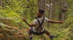 A man riding a zip wire on his work ream building away day at Go Ape Bedgebury