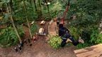 Woman in black hoodie and beanie jumping off platform on Go Ape Plummet